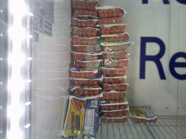 Beef franks stacked on each other on the shelf of a fridge.